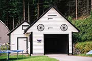 写真：白の板塀の入口の上に車輪を二つ飾った車庫